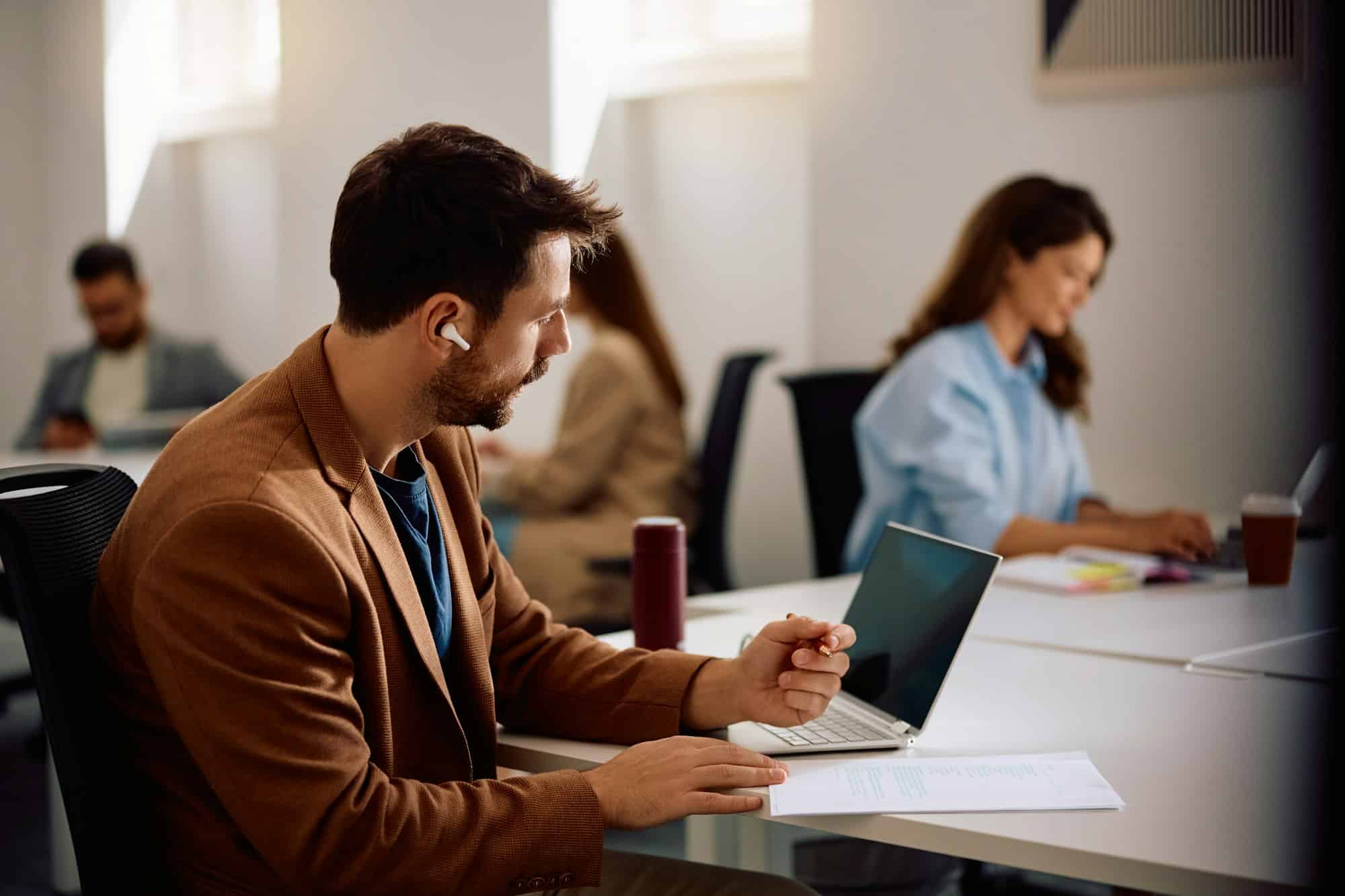 Profissionais de marketing colaborando em estratégias híbridas utilizando tecnologia e ferramentas digitais.